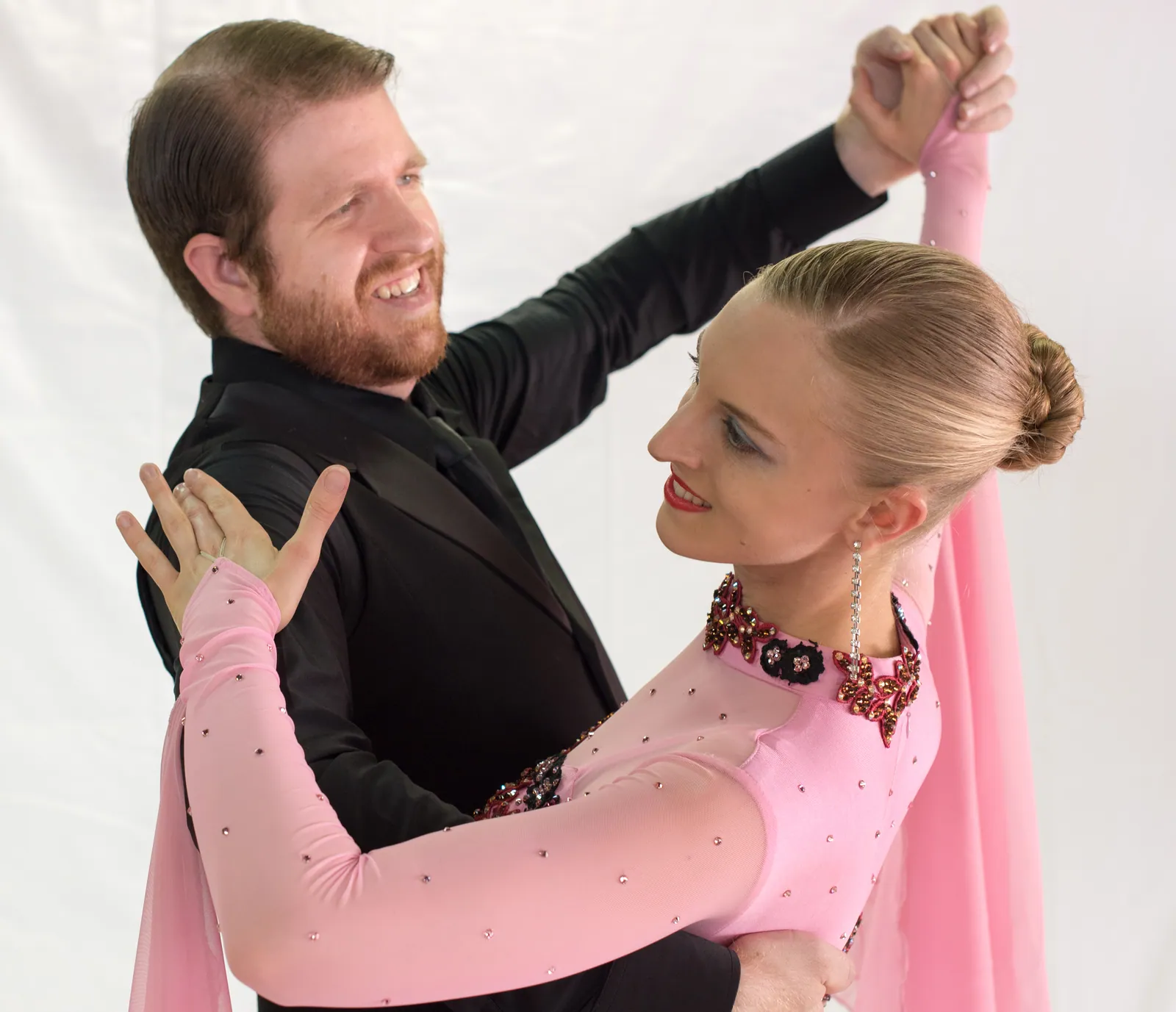 Eric and Bria smiling in a connected ballroom frame, from their dance archive